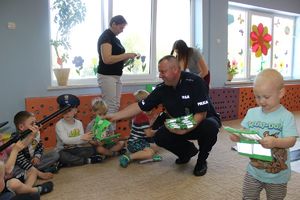 policjant rozdaje dzieciom kamizelki odblaskowe
