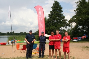 policjanci z ratownikami na plaży jeziora