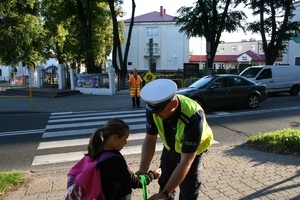 policjant zakłada dziewczynce opaskę odblaskową