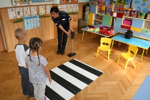 policjantka z 2 dzieci przy macie przejścia dla pieszych
