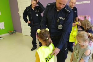 dzieci w policyjnych kamizelkach z policjantem