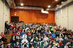 uczniowie siedzą w fotelach sali widowiskowej szkoły