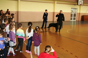 policjantka i przewodnik psa prezentują uczniom psa służbowego