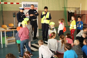 policjantka i dzieci ubrani w kamizelki i czapki odblaskowe