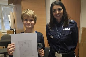 chłopiec z policjantką pokazuje zabezpieczoną odbitkę dłoni